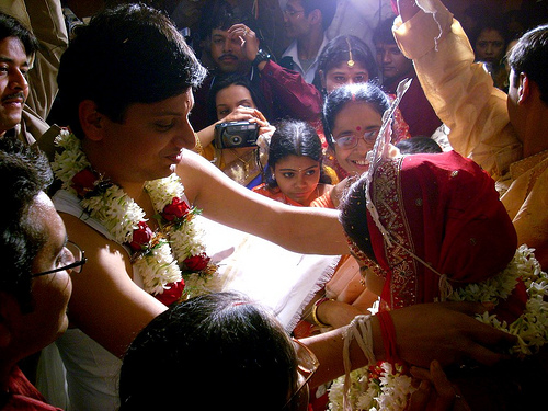 Bride and groom exchanging flower garlands at a Bengali wedding