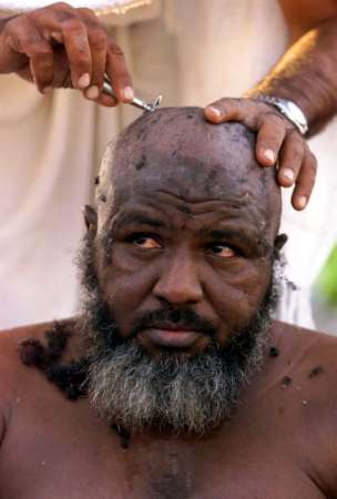 A Hajj pilgrim has his head shaved